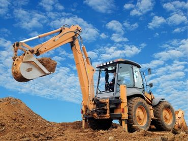 A backhoe loader raising a bucket load of soil.