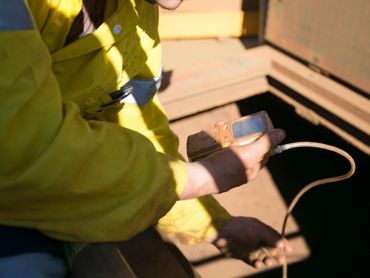 Person holding a Gas Test monitor as they check a confined space for toxic gases.